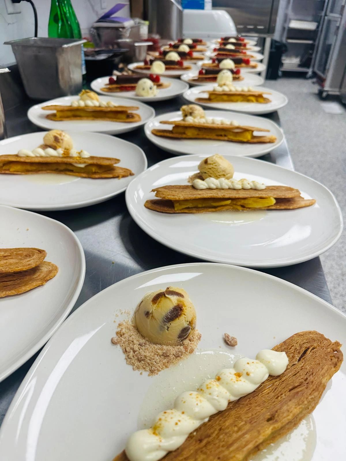 Plates of desserts with chocolate-covered pastries, raspberries, and ice cream scoops.